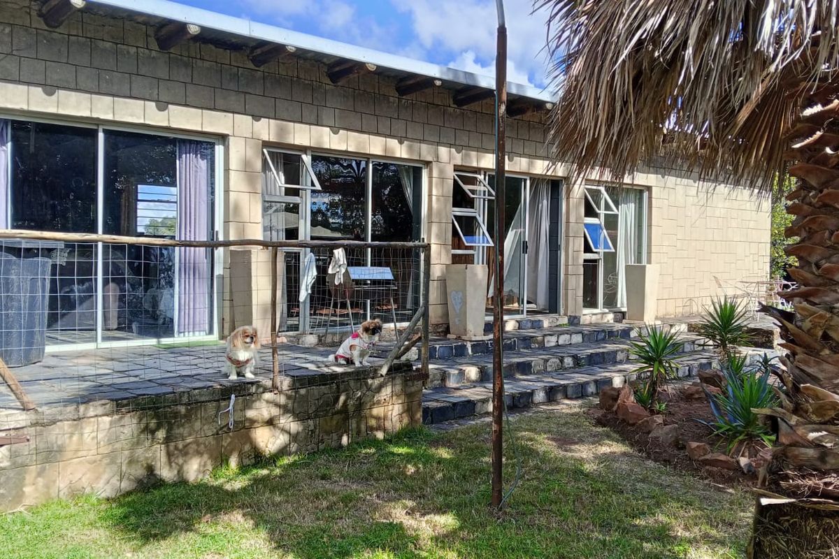 A rear exterior view of the apartment featuring a stone-paved patio, sliding glass doors, and a low-maintenance garden area.