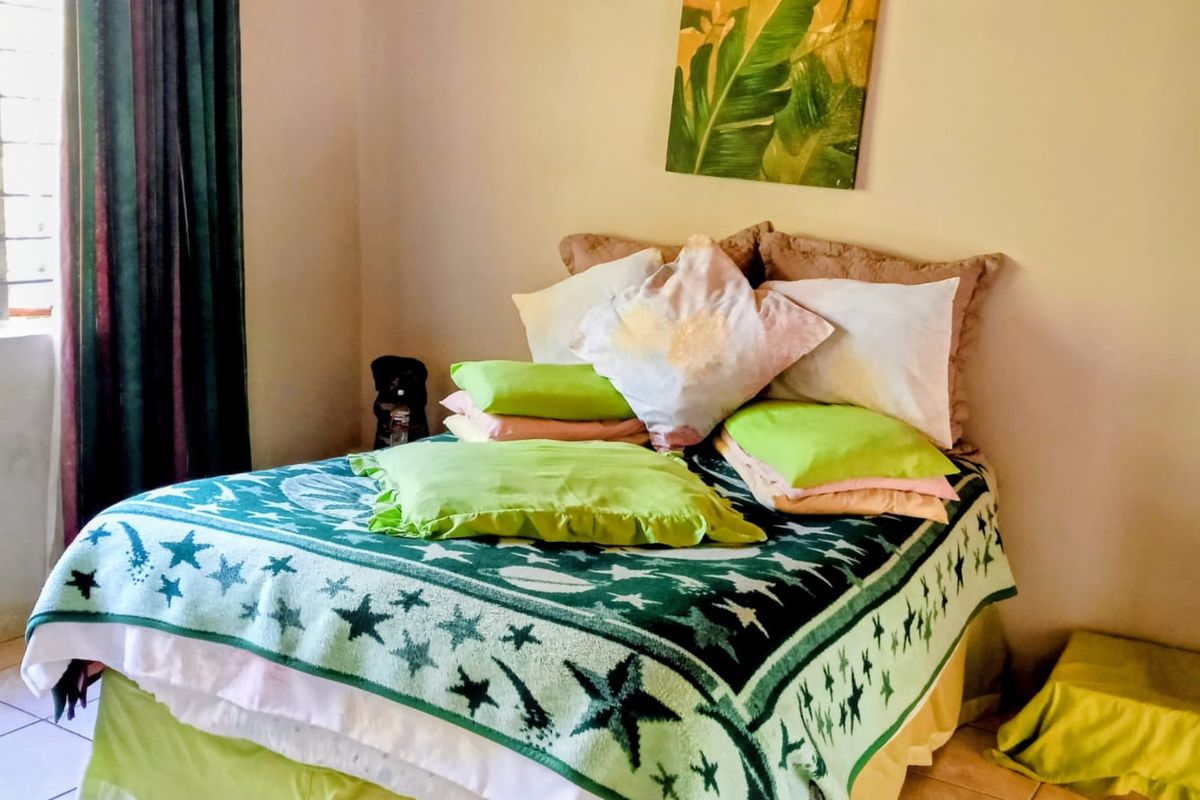 A bedroom featuring tiled flooring and a window with security bars, providing natural light to the space.