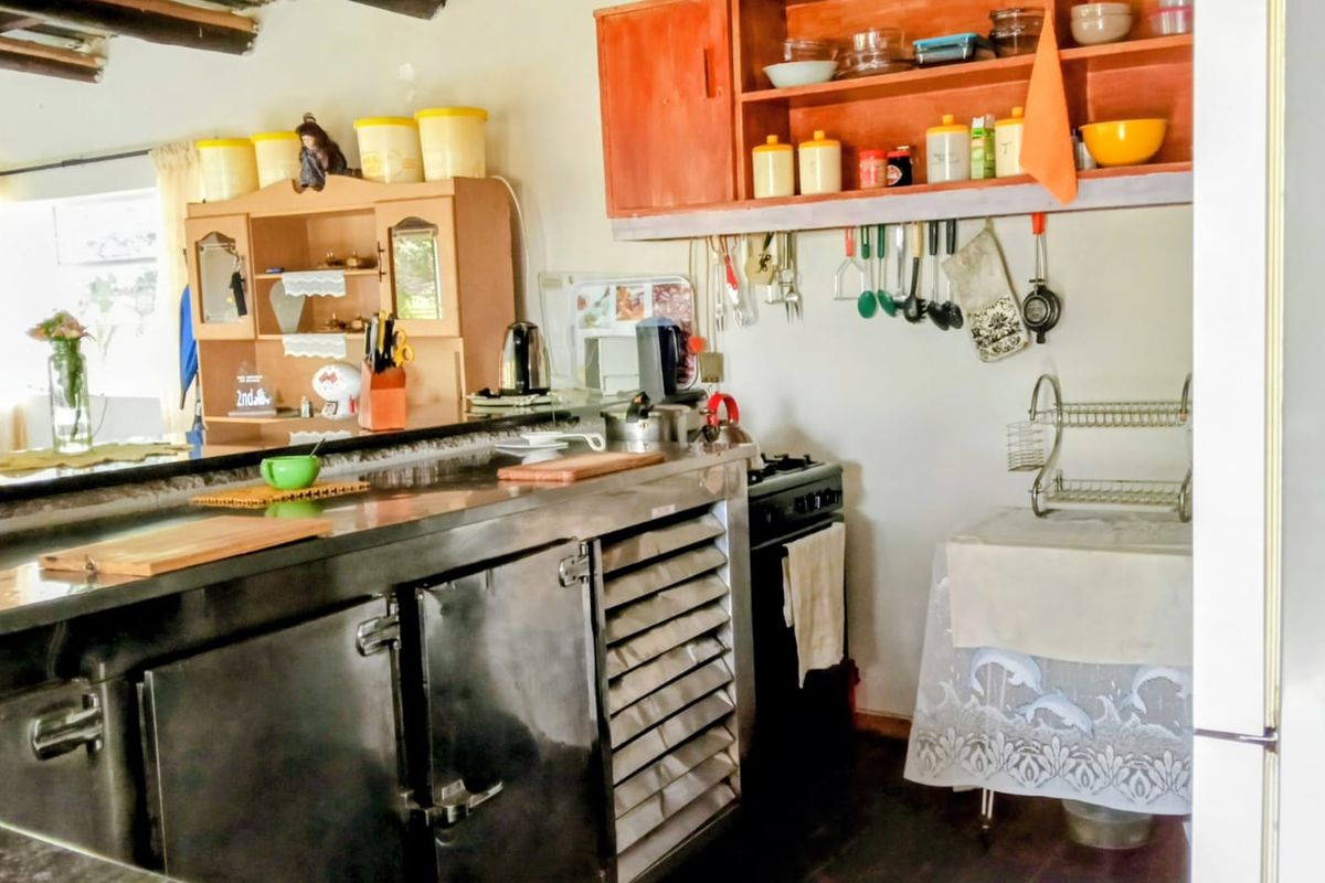 A functional kitchen area featuring stainless steel countertops, open shelving, and a built-in stove, offering a practical layout for daily meal preparation.