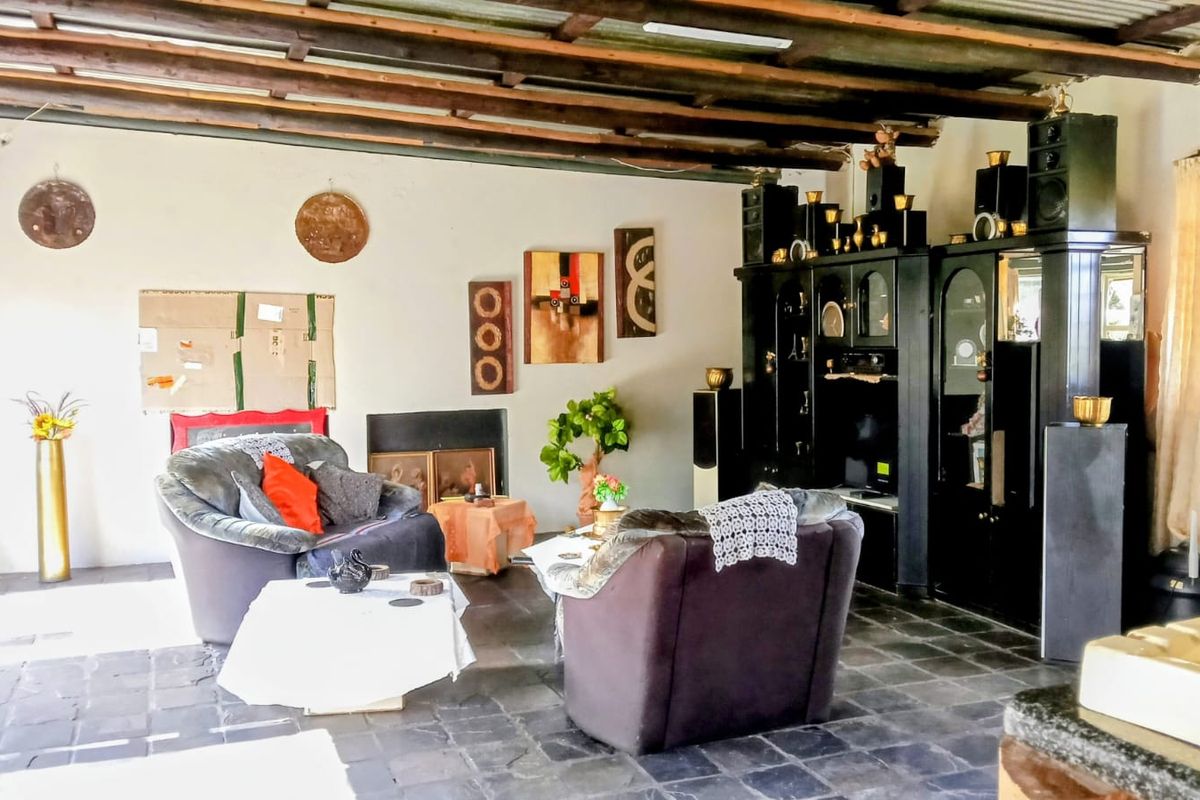 A spacious living area featuring exposed timber ceiling beams and dark tiled flooring, offering a rustic aesthetic with potential for modernization.