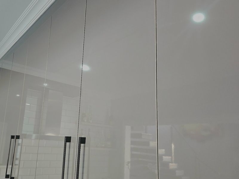 Modern kitchen featuring high-gloss cabinetry with sleek black handles and elegant crown molding, providing a clean and contemporary aesthetic.