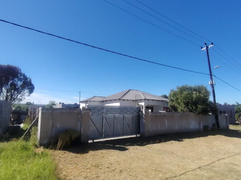 Front view of the property featuring a perimeter wall, metal driveway gate, and tiled roof structure.