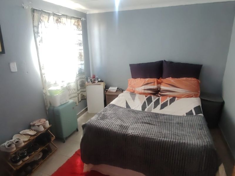 A compact bedroom featuring grey walls and a central ceiling light fixture, requiring minor cosmetic updates to improve the overall finish.