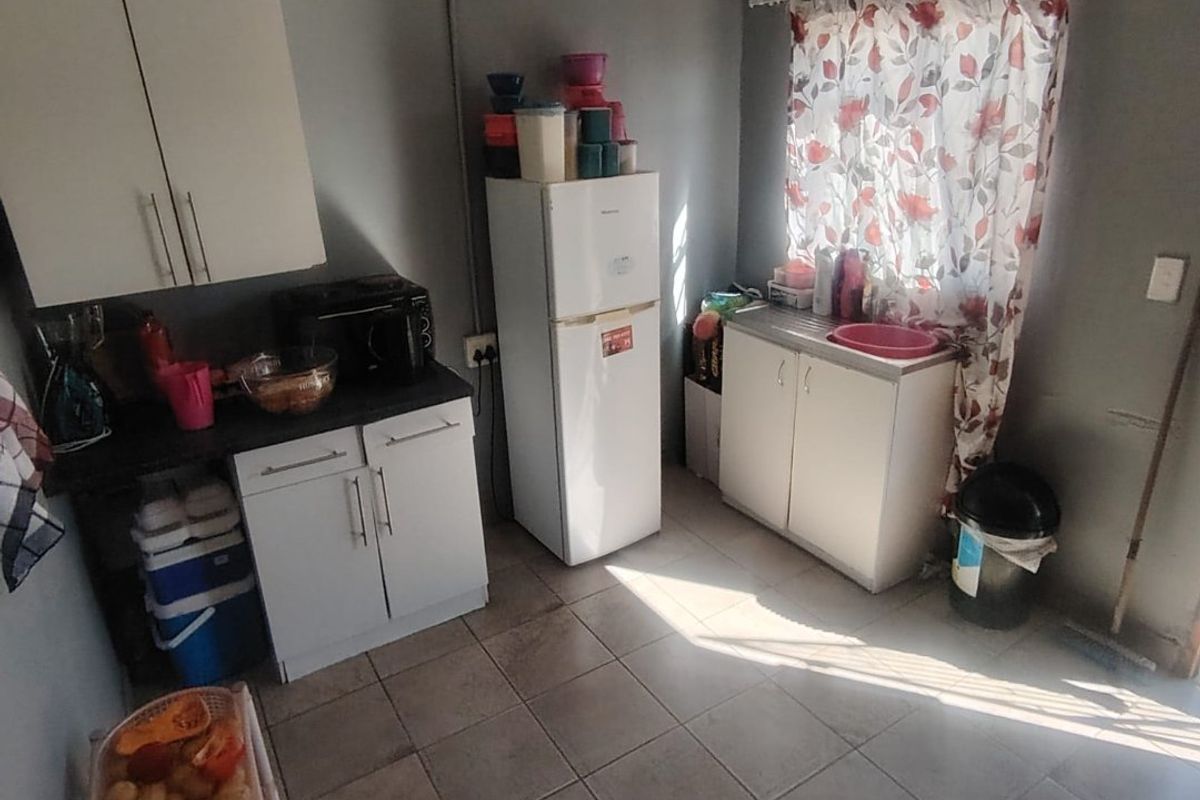 A compact kitchen featuring basic built-in cabinetry, laminate countertops, a stainless steel sink, and tiled flooring, requiring cosmetic updates to improve functionality and aesthetic appeal.