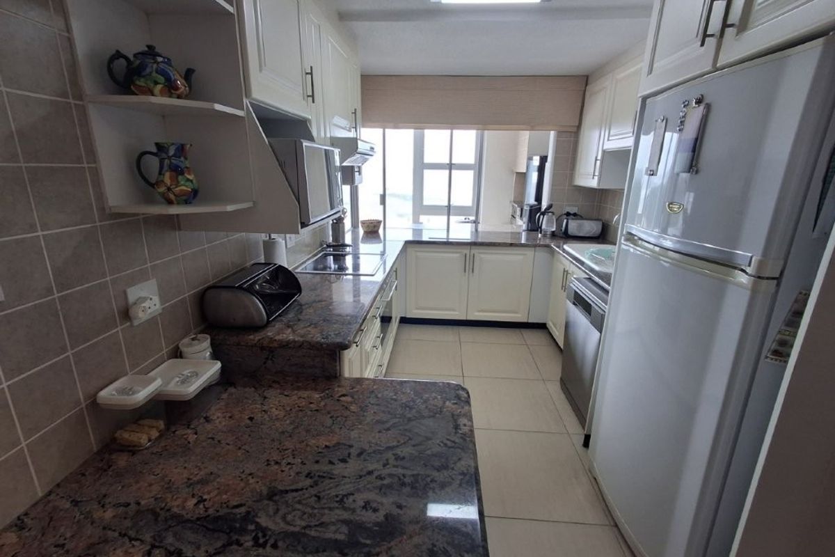 A functional kitchen featuring granite countertops, ample built-in cabinetry, tiled backsplash, and ceramic flooring, offering a practical layout with natural light.
