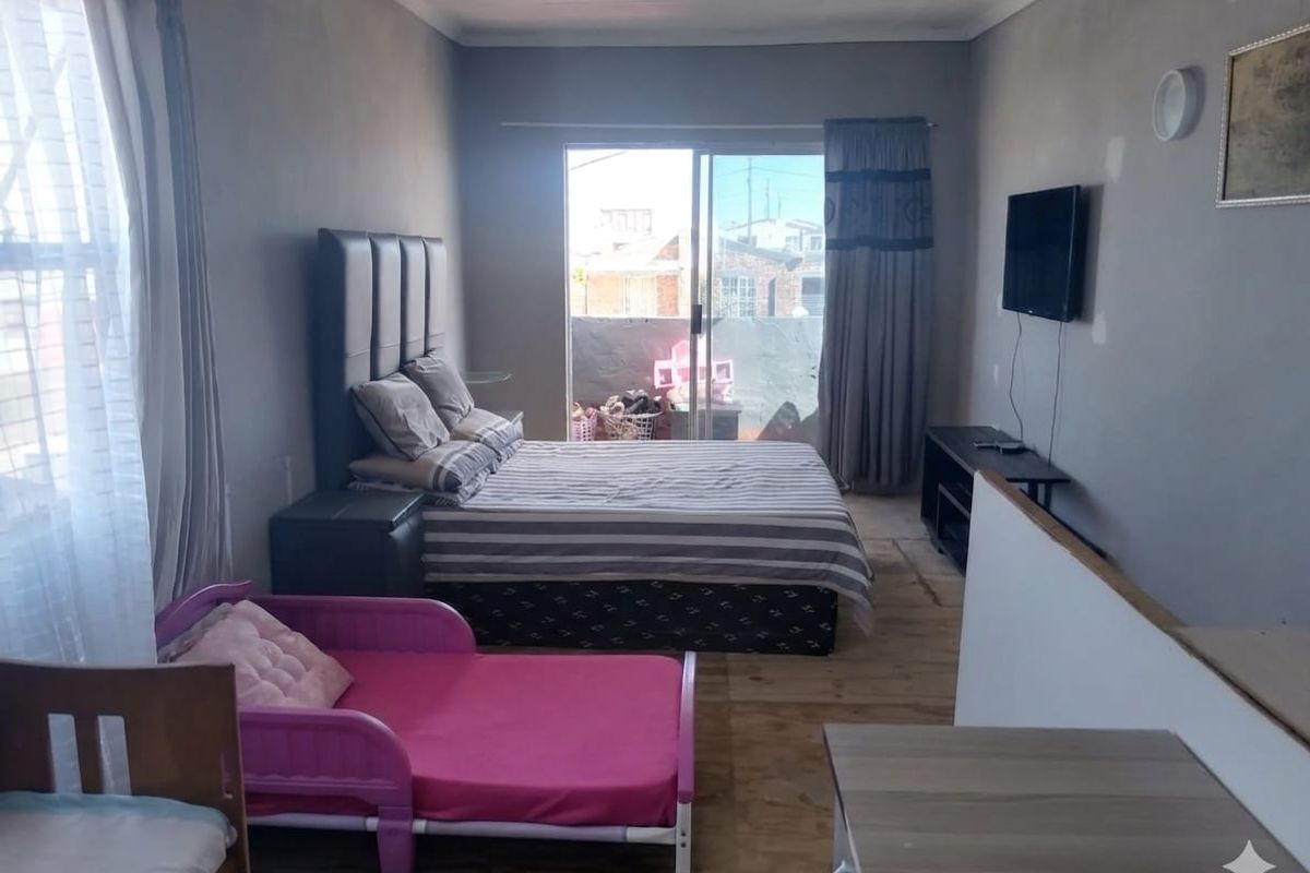 A bedroom featuring laminate flooring and a sliding glass door leading to an outdoor area, with walls requiring finishing and paint.