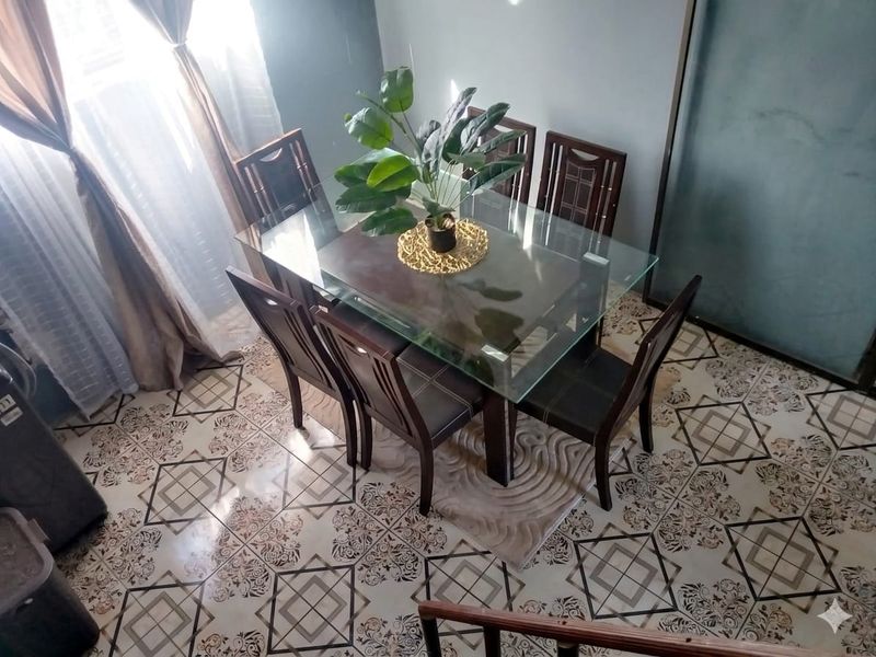 A dining area featuring decorative patterned floor tiles and natural light from adjacent window treatments.