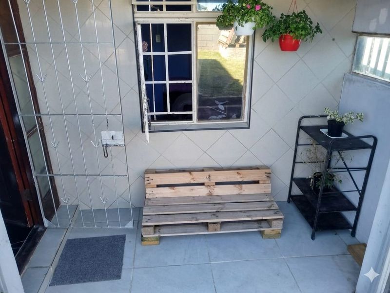 A covered patio area featuring tiled flooring, tiled wall finishes, and a secure entrance gate with window security bars.