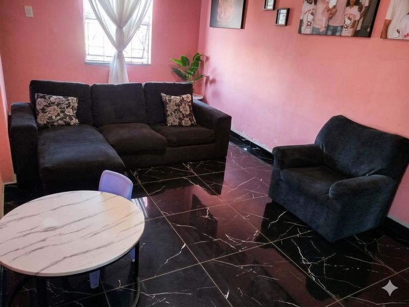 Living room featuring dark marble-look floor tiles and pink wall finishes, with security bars installed on the window.