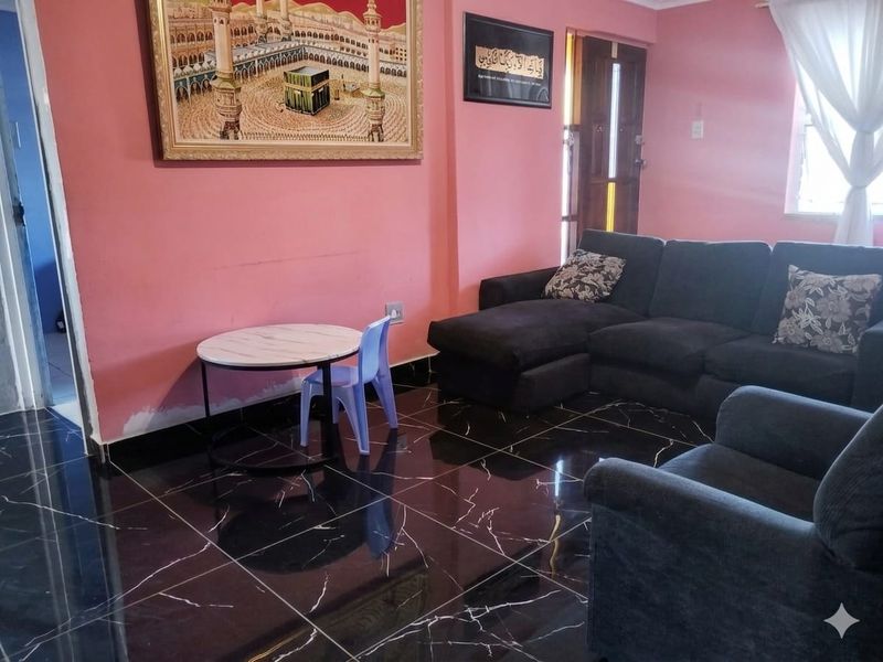 A living room featuring dark marble-effect floor tiles and pink walls, with a timber-framed entrance door and visible wall finish work required.