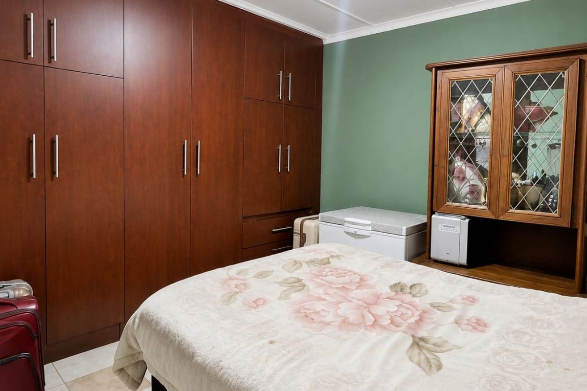 A bedroom featuring extensive floor-to-ceiling built-in wooden cupboards and tiled flooring, offering ample storage space.