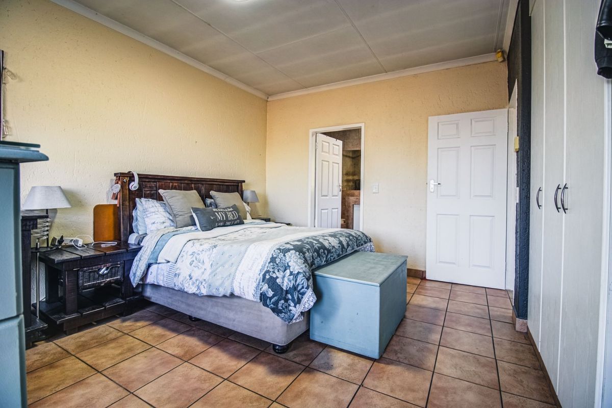A bedroom featuring tiled flooring, built-in cupboards, and direct access to an en-suite bathroom.