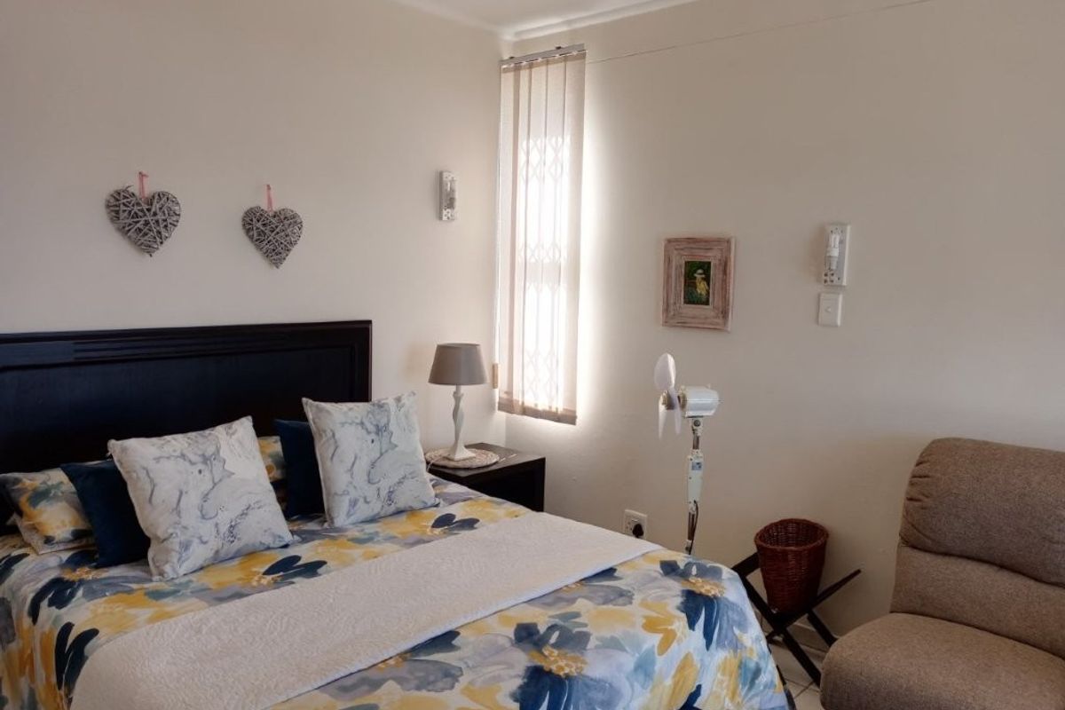 A well-maintained bedroom featuring neutral wall finishes, vertical window blinds, and standard electrical fixtures.