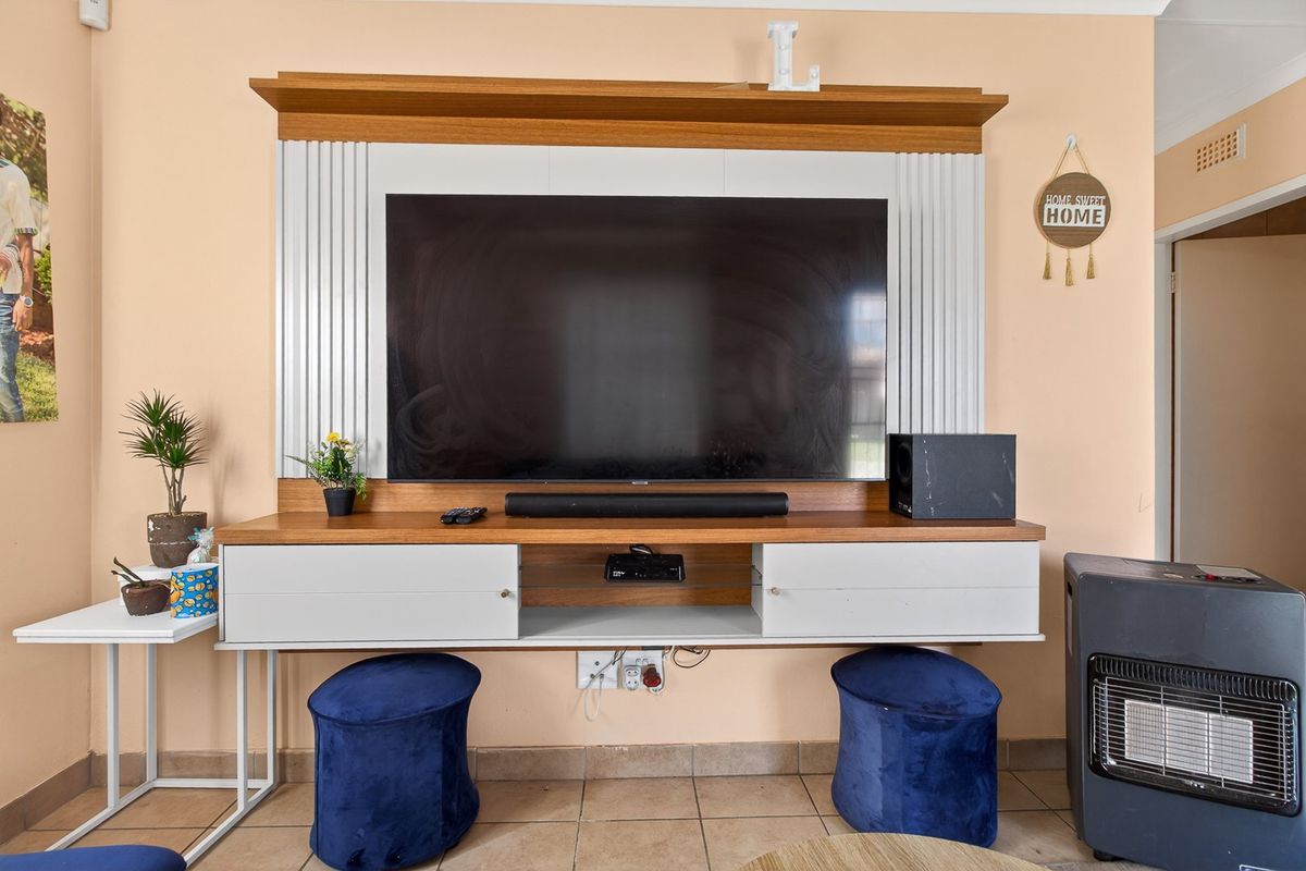 A living room featuring a built-in media unit with integrated shelving and cabinetry, set against a neutral wall with tiled flooring.