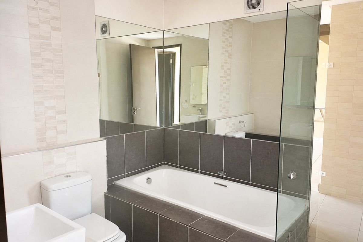 Modern bathroom featuring a built-in bathtub, large wall-mounted mirror, glass shower screen, and neutral tiled finishes.