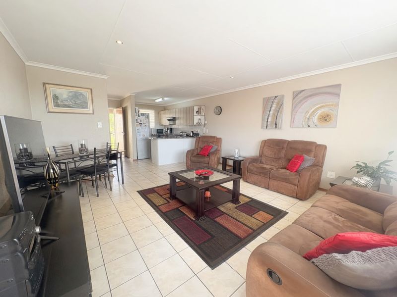 Spacious open-plan living and dining area featuring tiled flooring, recessed lighting, and a functional kitchen with island cabinetry.
