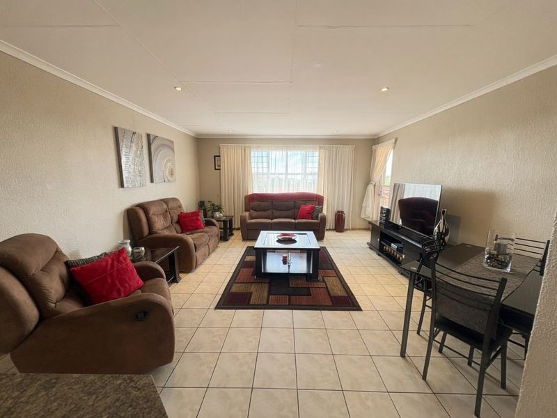 Spacious open-plan living and dining area featuring neutral tiled flooring, recessed lighting, and coved ceiling finishes.