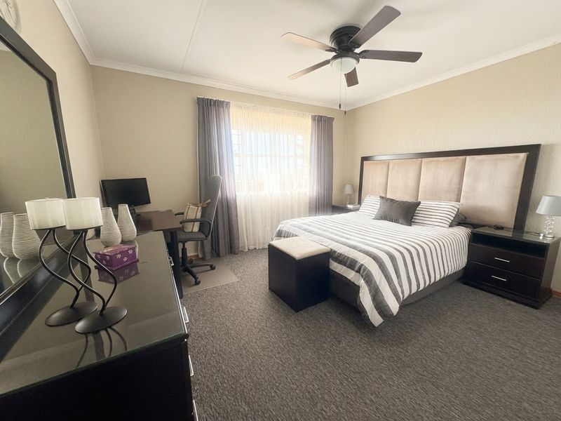 A well-maintained bedroom featuring carpeted flooring, a ceiling fan, and neutral wall finishes, providing a comfortable and functional living space.