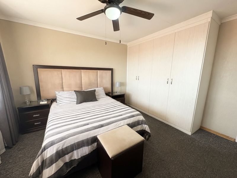 A well-maintained bedroom featuring neutral walls, dark carpeting, and ample built-in cupboard storage space.