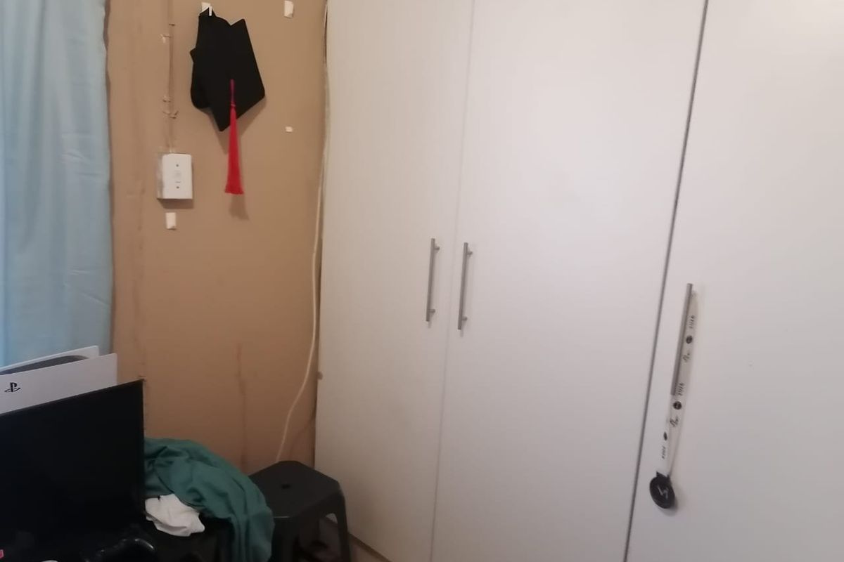 A bedroom featuring a built-in wardrobe with white doors, requiring wall finishing and electrical maintenance.