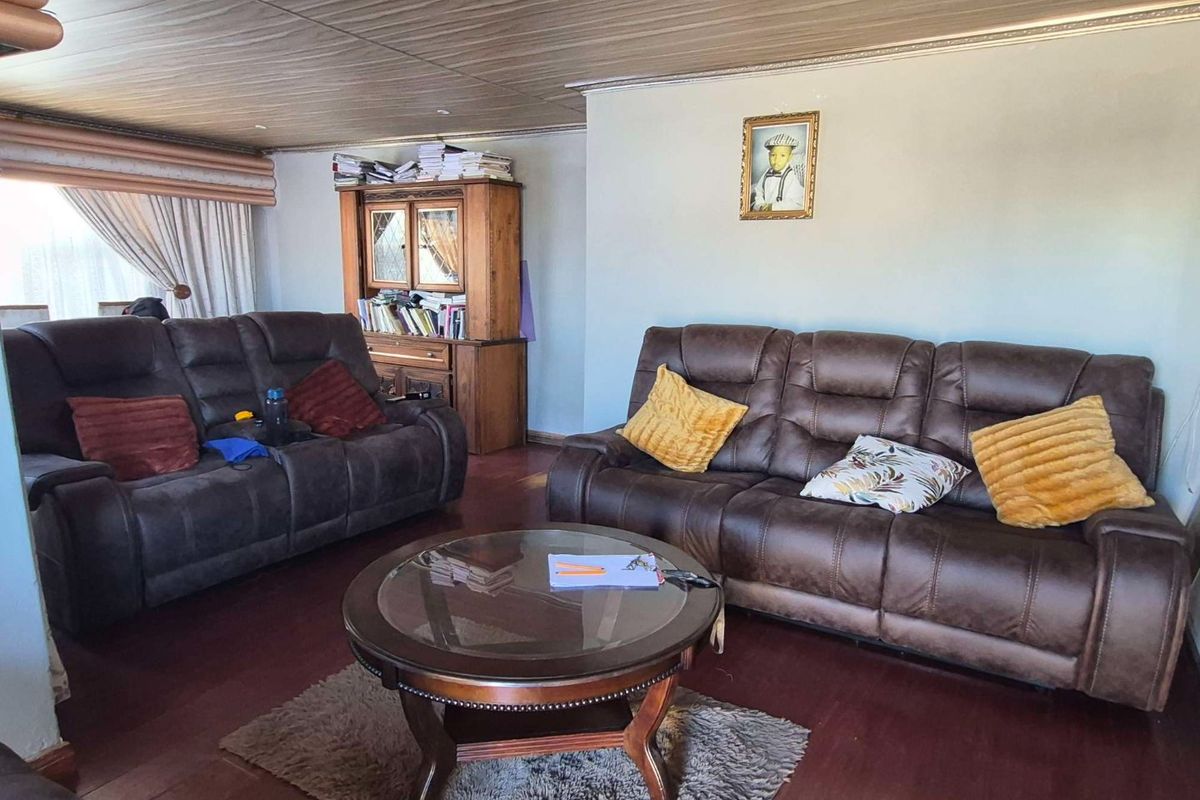 A living room featuring dark laminate flooring and a textured ceiling, providing a functional space for relaxation.