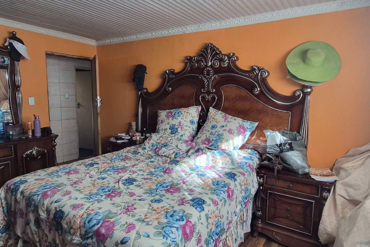 A bedroom featuring laminate flooring and a coved ceiling, currently requiring cosmetic updates to the wall and ceiling finishes.