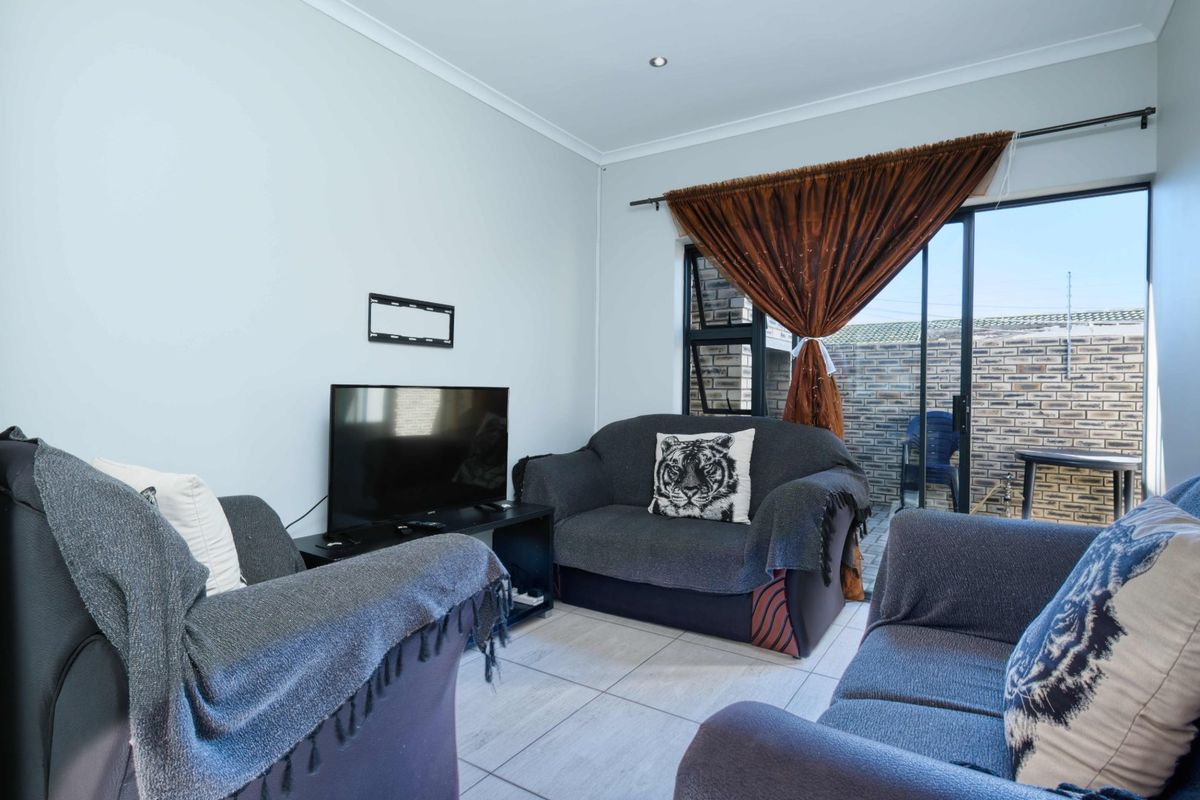 A living room featuring tiled flooring and a sliding glass door providing access to an outdoor patio area.