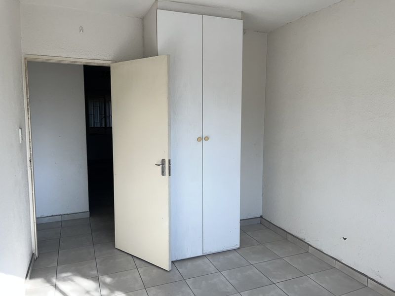 An empty bedroom featuring tiled flooring and a built-in wardrobe, offering a blank canvas for personalization.