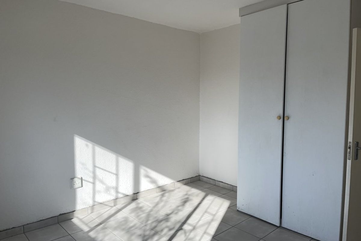 An empty bedroom featuring tiled flooring and a built-in wardrobe, offering a blank canvas for personalization.
