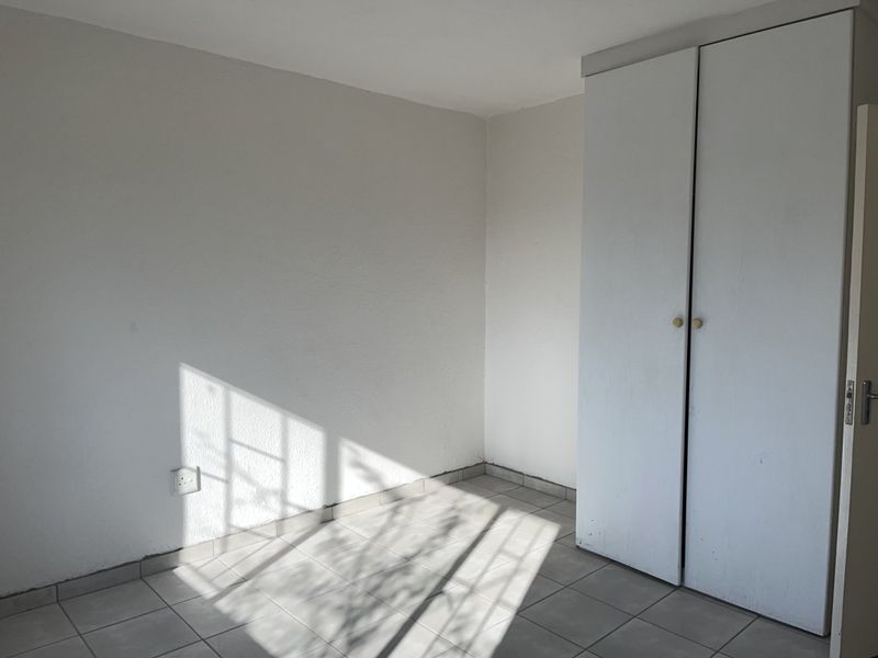 An empty bedroom featuring tiled flooring and a built-in wardrobe, offering a blank canvas for personalization.