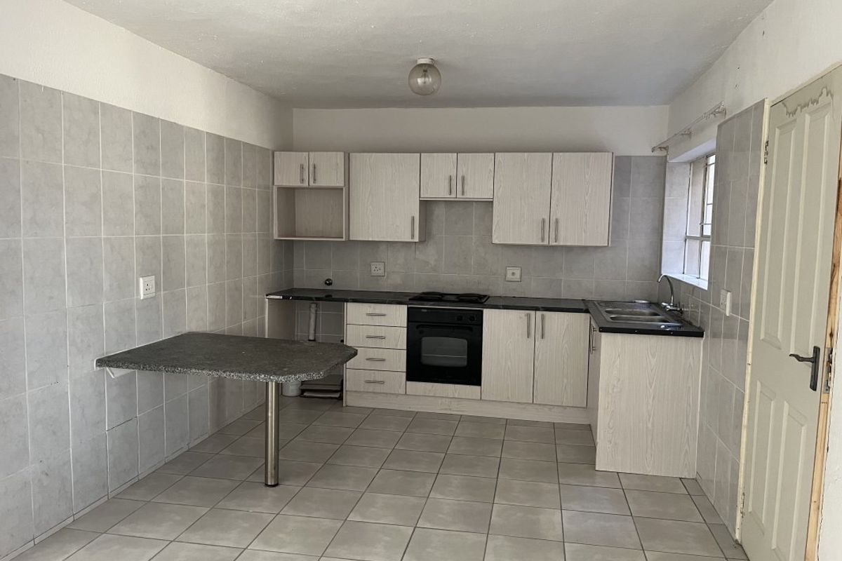 A functional kitchen featuring built-in cabinetry, integrated oven and hob, tiled backsplash, and a convenient breakfast bar area.