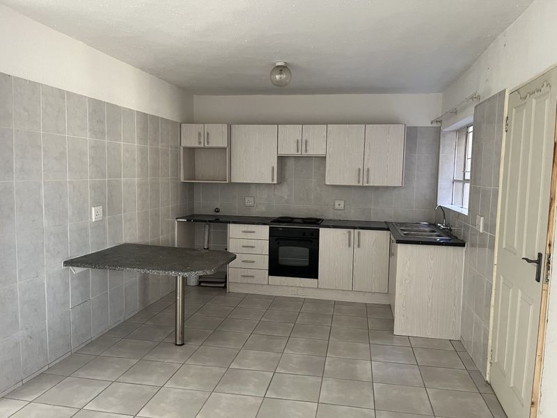 A functional kitchen featuring built-in cabinetry, integrated oven and hob, tiled backsplash, and a convenient breakfast bar area.