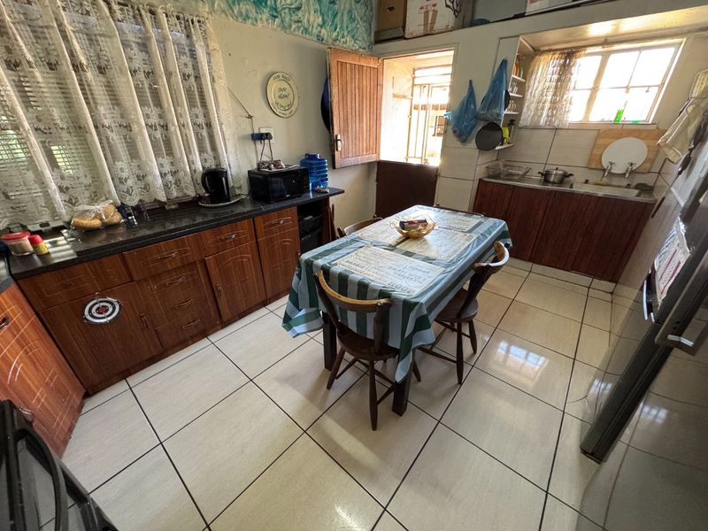 A functional kitchen featuring laminate cabinetry, granite countertops, tiled flooring, and direct access to an exterior door.