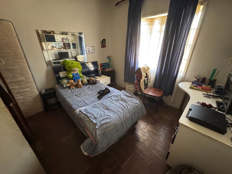 A bedroom featuring parquet flooring and a large wall-mounted mirror, offering a functional space with potential for cosmetic updates.