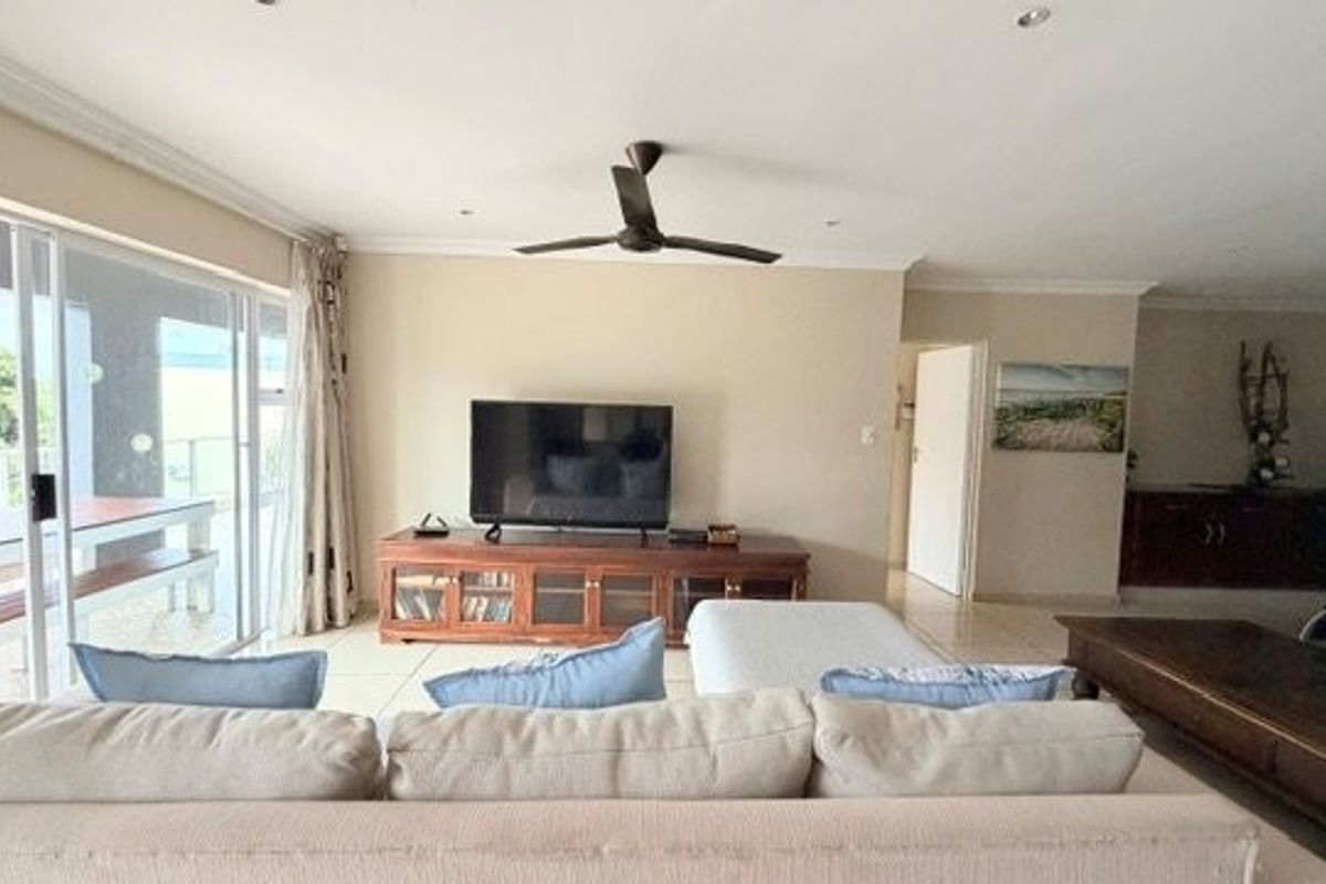 Spacious living room featuring tiled flooring, recessed lighting, a ceiling fan, and large sliding glass doors providing access to the outdoor area.