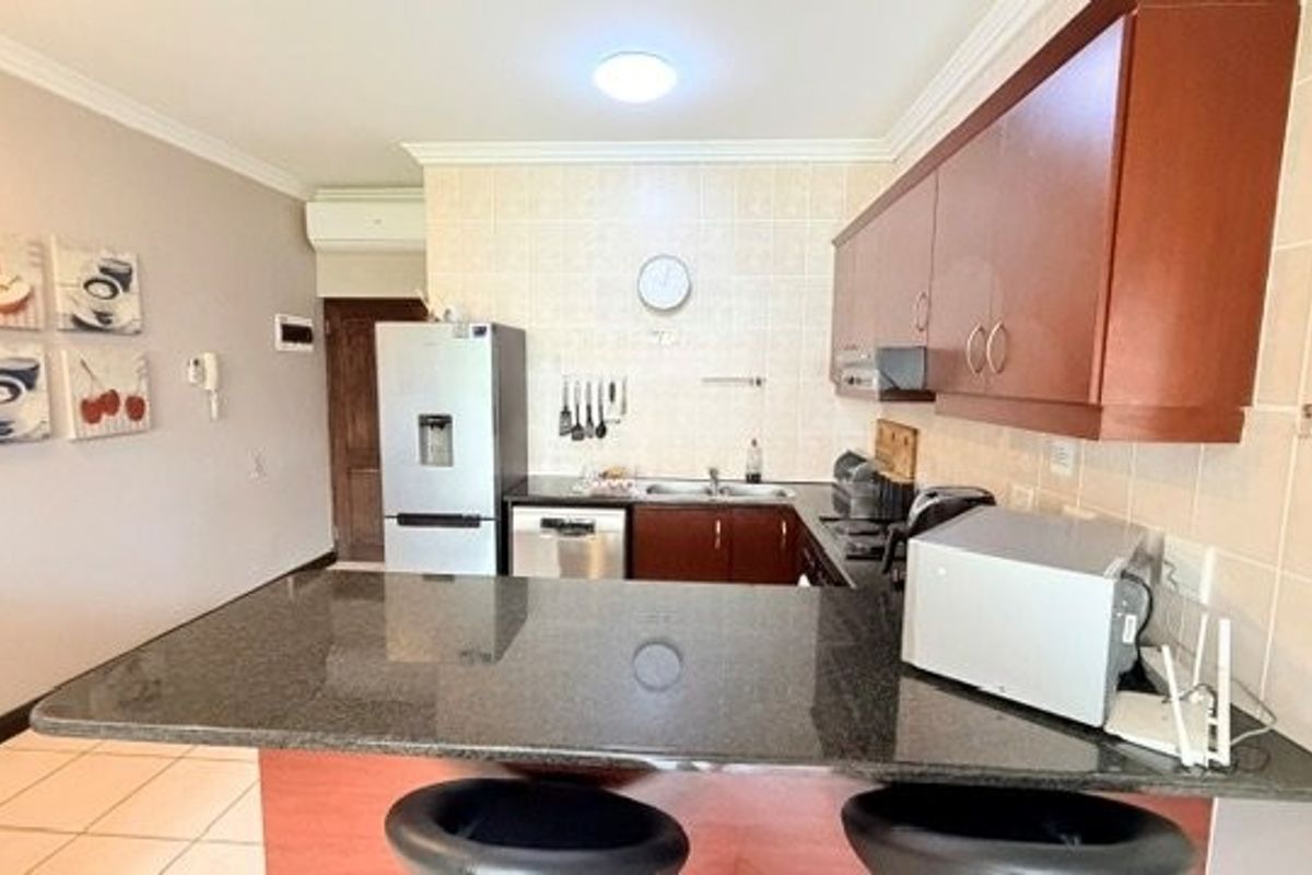 Functional kitchen featuring dark wood cabinetry, granite countertops, a breakfast bar, and tiled backsplash, providing a practical workspace for daily meal preparation.