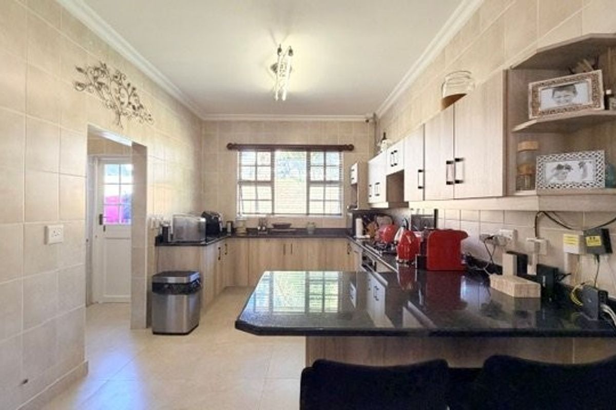 A functional kitchen featuring granite countertops, ample built-in cabinetry, tiled walls, and a breakfast bar area with direct access to an exterior door.