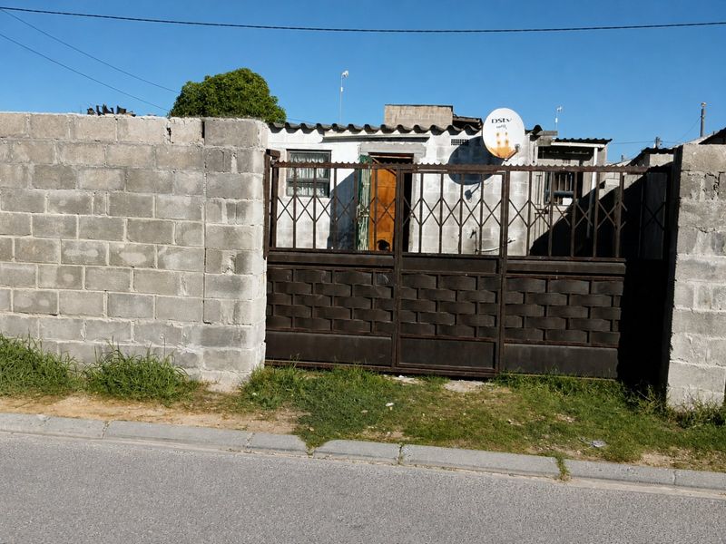 Front view of a property featuring a concrete block perimeter wall, metal security gate, and exterior facade with security bars on windows.