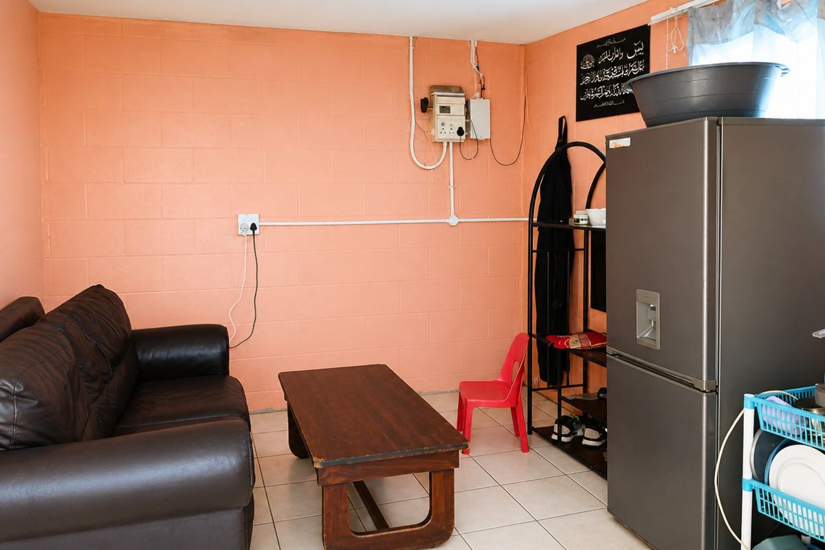 A living area featuring tiled flooring and exposed electrical infrastructure on the walls, presenting an opportunity for cosmetic updates and improved cable management.