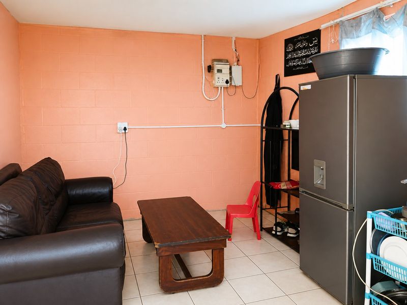 A living area featuring tiled flooring and exposed electrical infrastructure on the walls, presenting an opportunity for cosmetic updates and improved cable management.