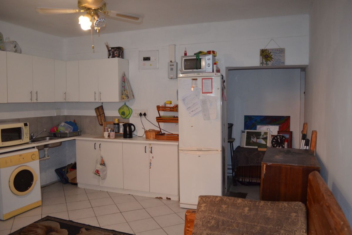 A functional kitchen area featuring white cabinetry, tiled flooring, and a ceiling fan, offering a practical layout for daily use.