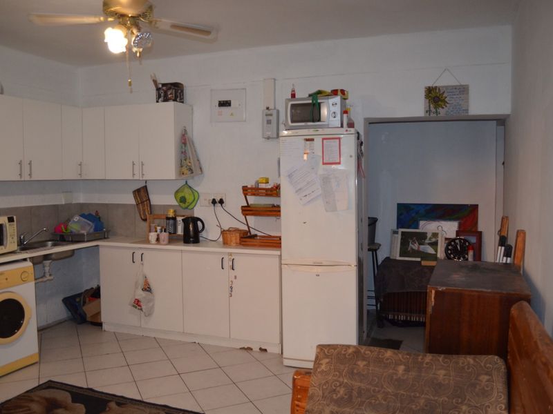 A functional kitchen area featuring white cabinetry, tiled flooring, and a ceiling fan, offering a practical layout for daily use.