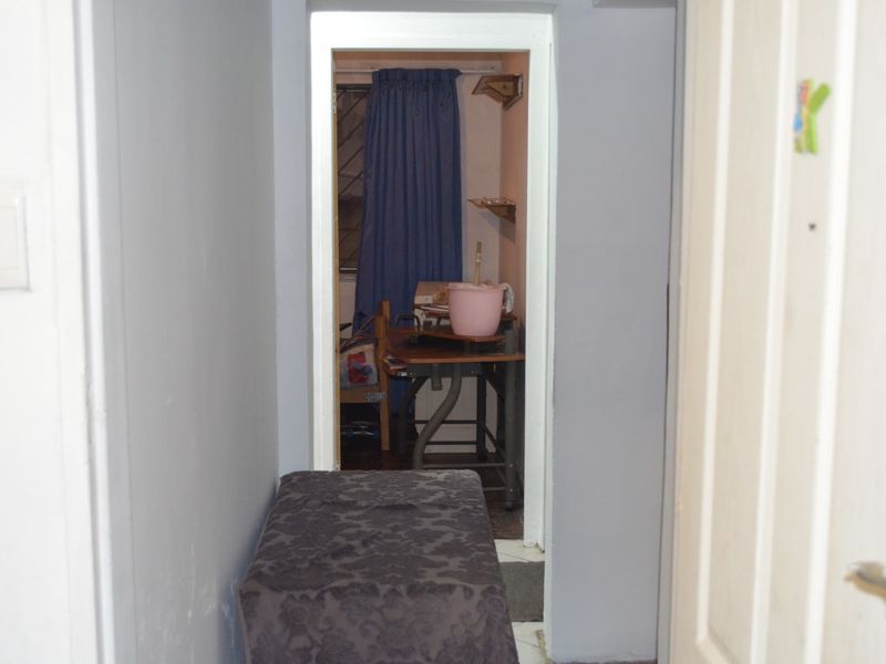 A narrow interior hallway leading into an adjacent room, featuring plain wall finishes and standard door frames.