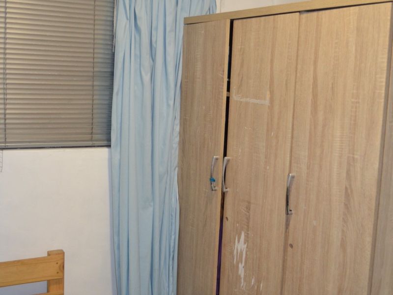 A bedroom featuring a built-in wardrobe and venetian blinds, requiring cosmetic updates to improve the overall condition and aesthetic appeal.