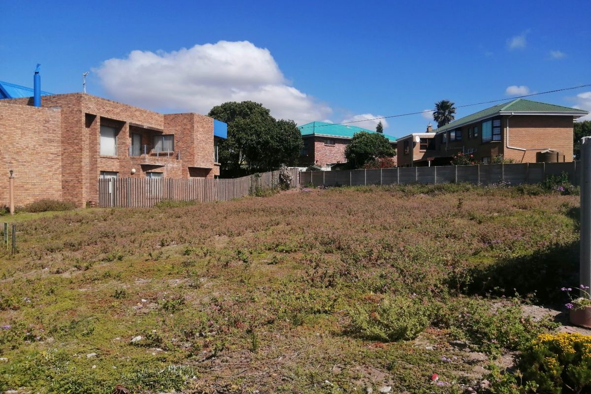 A vacant residential plot of land featuring perimeter fencing and a concrete boundary wall, situated in an established neighborhood.