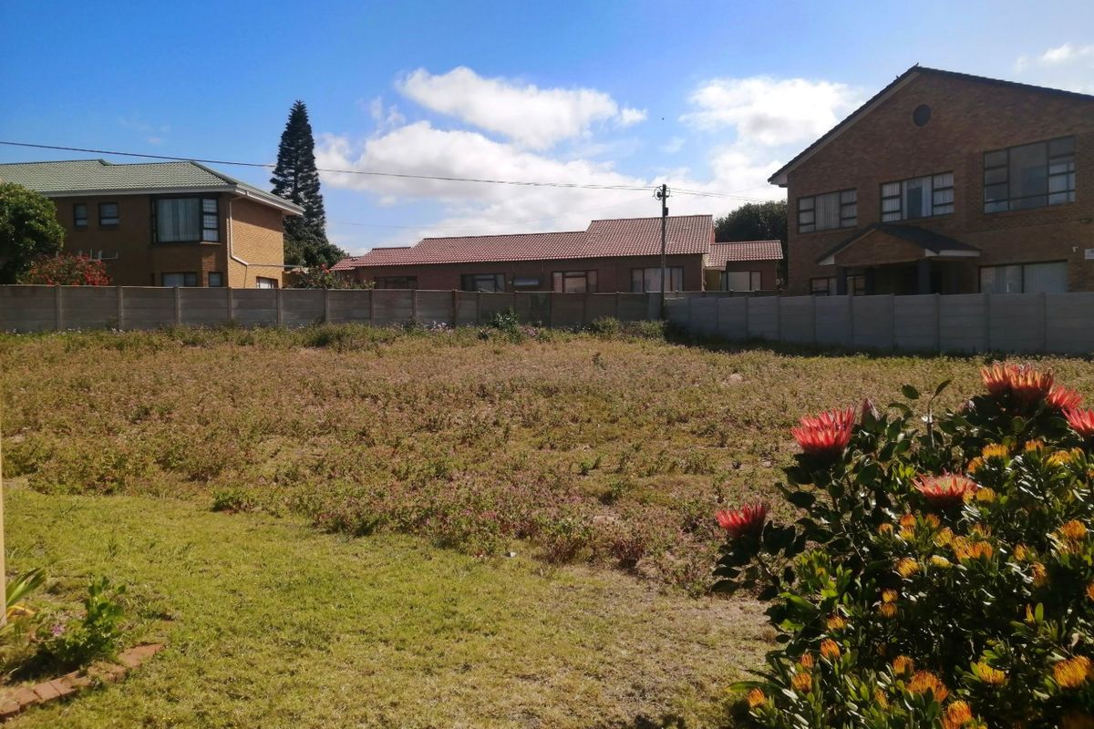 A vacant residential plot featuring a level grassed area enclosed by precast concrete boundary walls in a suburban neighborhood setting.