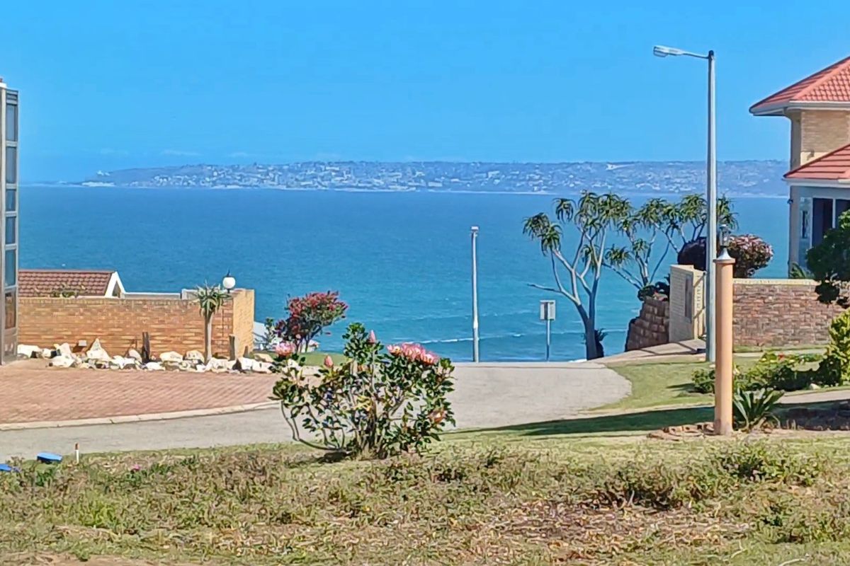 A scenic view of the ocean and coastline from the residential property, featuring established landscaping and paved access.