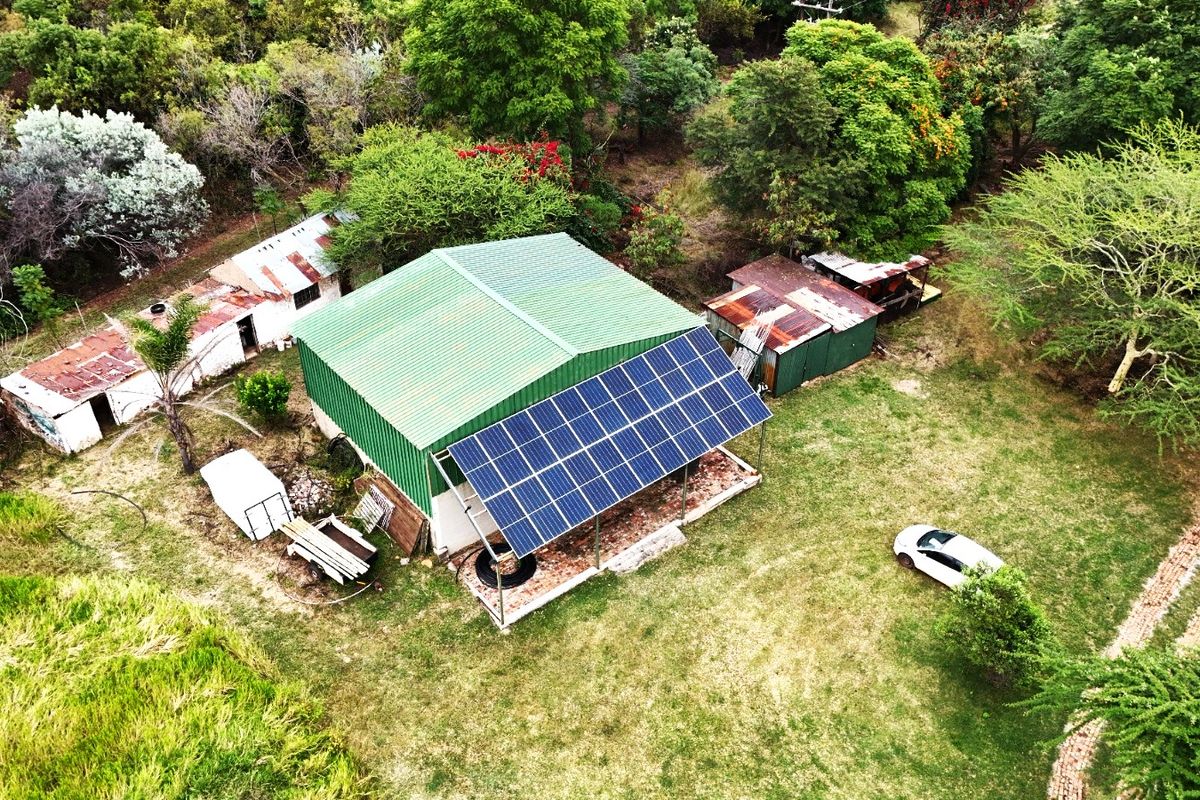 Aerial view of a farm property featuring a main structure with solar panels and several smaller outbuildings set within a rural landscape.