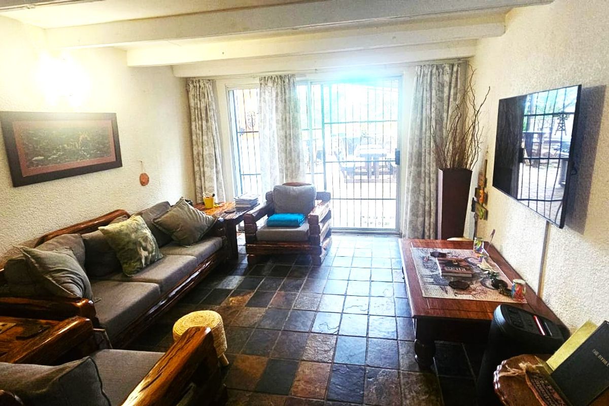 Cozy living room featuring rustic slate tile flooring, exposed ceiling beams, and a sliding glass door providing access to the outdoor area.