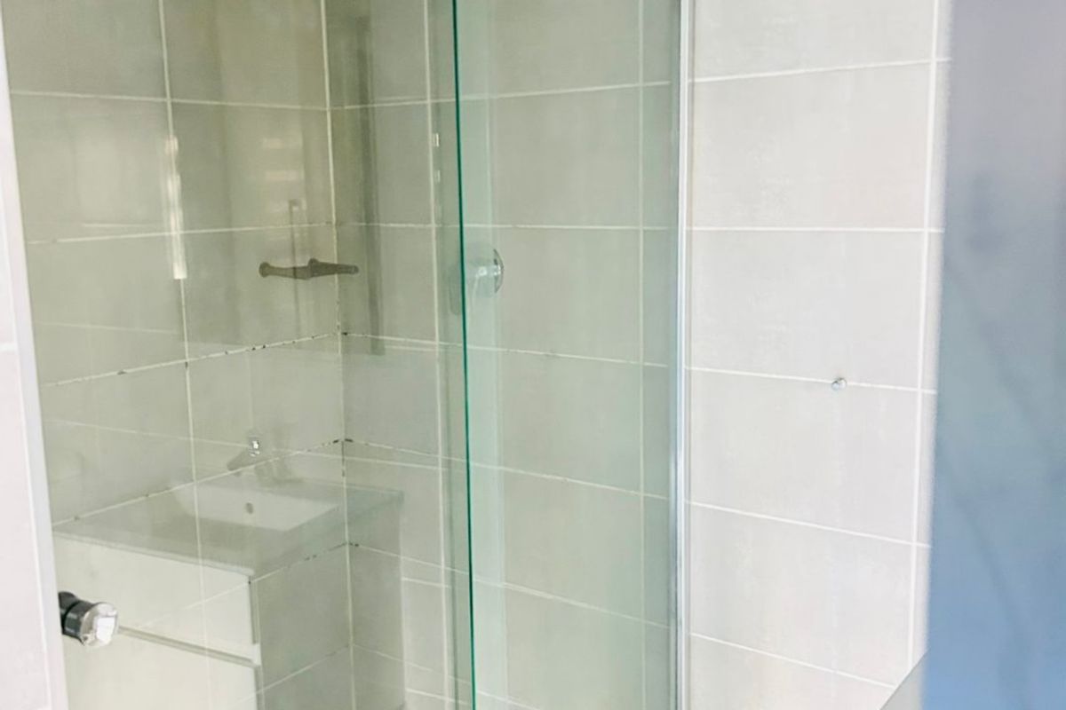 A clean bathroom featuring a glass-enclosed shower, tiled walls, and a modern vanity unit with a basin.
